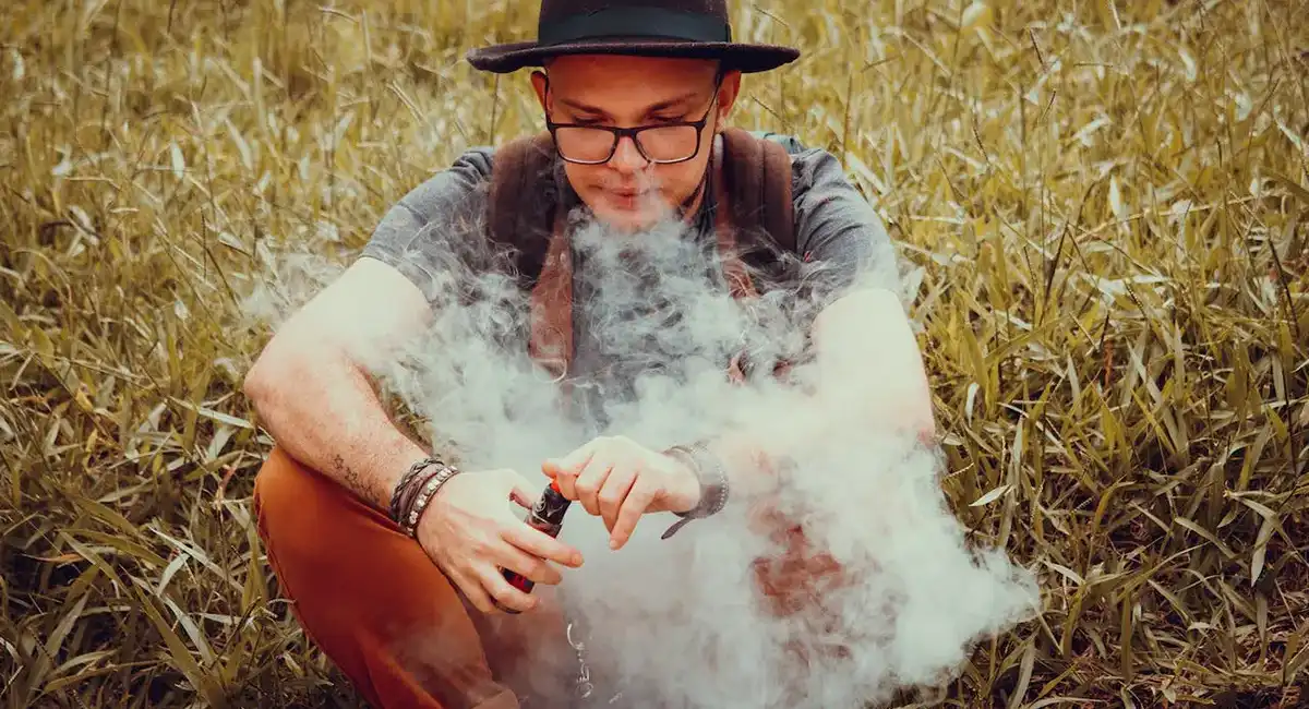Mastering Vape Tech: What is Mesh Coil in Vapes? a man sitting in the field and vaping provided by the vape coil