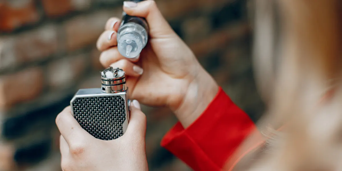 stylish woman fills the vape juice into the vape coil