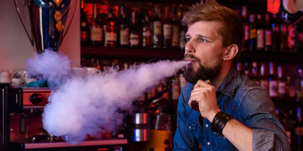 Why is My Disposable Vape Light Staying On? man is taking disposable vape in a vape shop